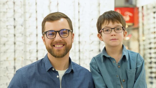 Little boy in new glasses with his father at optics shop