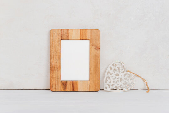Mockup wooden picture frame and toy heart against white heart. Valentines day concept. Copy space