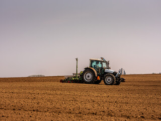 Fototapeta premium Farmer planting soybean seeds in a field with a tracto
