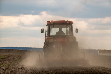 Fototapeta premium Springtime seeding preparations, tractor at work on the fertile fields
