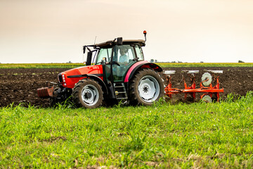 Tractor plowing and preparing stubble field for cultivating and seeding crops