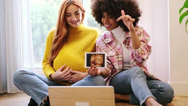 4k video of a couple of women showing the ultrasound online in a video call. Concept: motherhood, pride, connection