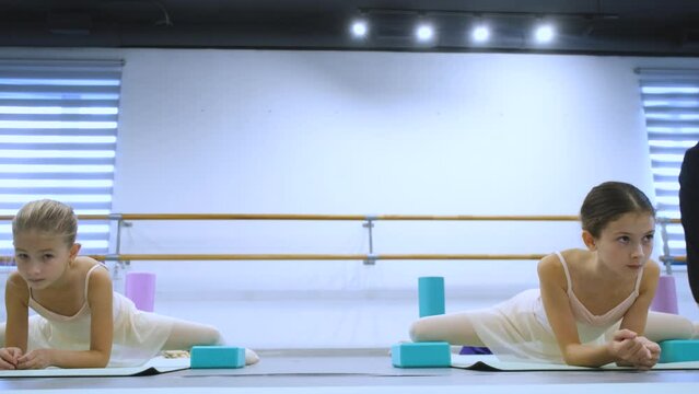 girls in dance class doing stretching on the floor