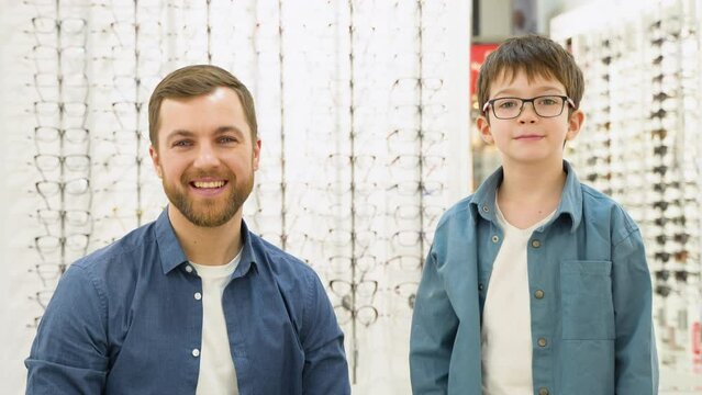 Little boy in new glasses with his father at optics shop. Ophthalmology concept