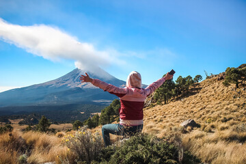 the Young Woman sitting on the Iztaccihuatl mountain at dawn in the background of the Popocatepetl volcano
