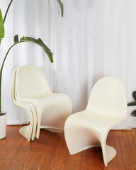 Set of white vintage molded plastic S chairs. Retro futuristic chairs stacked in a room before long...