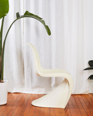 White vintage molded plastic S chair. Sife view of retro futuristic chair in a room before long...