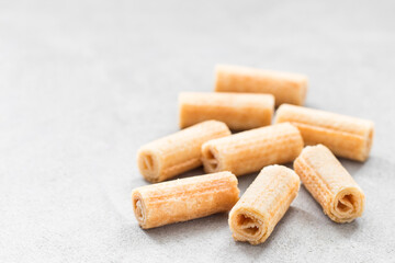 Mini sweet waffle rolls. Light grey background. Closeup. Copy space