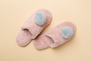 Soft pink slippers on color background, top view