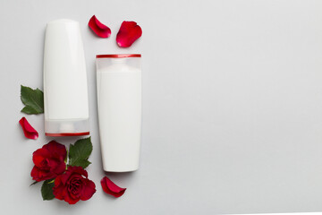 Hair care products and red roses on color background, top view