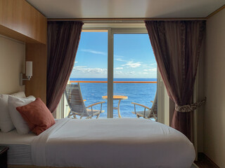 Cruise ship stateroom suite open to a balcony overlooking the beautiful blue ocean - 568594355