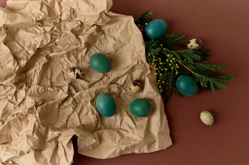 green colored eggs on a craft paper with a green branches on a brown background