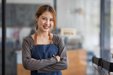 Shot of smiling young cafe show owner Asian woman standing with arms crossed and Open sign on the...