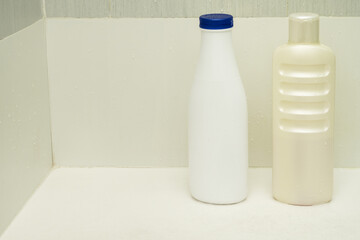shampoo bottles inside a bathroom with a white plate and clear glass partition