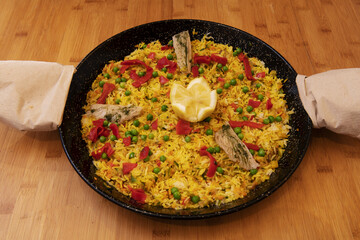 A Spanish paella espuenda in a paella pan with handles covered with napkins so as not to burn yourself when removing it from the heat