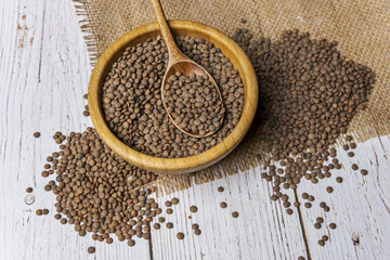 A bamboo bowl full of dried lentils on a white table