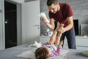 man caucasian father change diapers to his daughter toddler in bedroom - obrazy, fototapety, plakaty