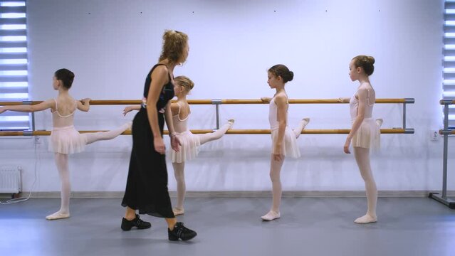 teacher teaches girls ballet at the barre