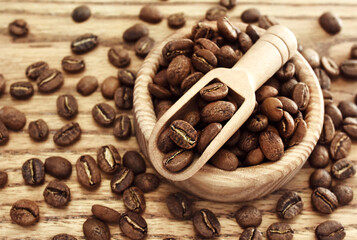 Roasted brown coffee beans in spoon on rustic wooden background
