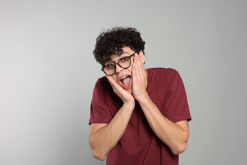 Portrait of shocked young man on light grey background