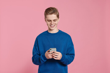 Teenage boy using smartphone on pink background © New Africa