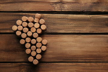 Fototapeta na wymiar Grape made of wine bottle corks on wooden table, top view. Space for text