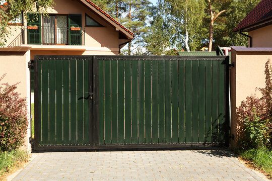 Green gates near house and trees outdoors
