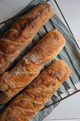 Fresh crispy ciabattas on white wooden table, top view