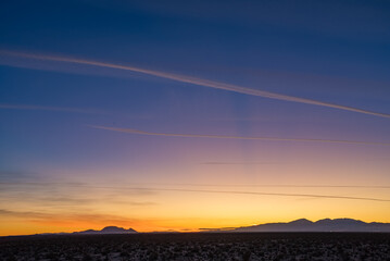 Orange purple gradient over mojave desert sunset with moutains