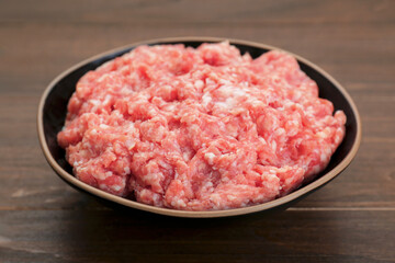 Bowl with raw fresh minced meat on wooden table, closeup
