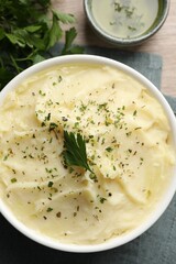 Bowl of delicious mashed potato with parsley on wooden table, flat lay