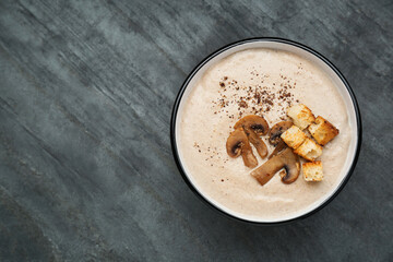 Delicious cream soup with mushrooms and croutons on black table, top view. Space for text