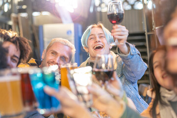 Young happy man toast with friends together in a party . Group of smiling people with colored hair celebrates drinking wine with friendship outside with sunshine