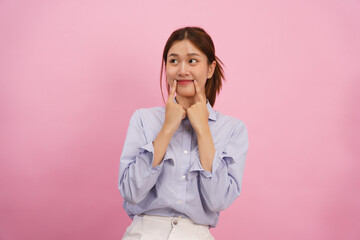 Women are touching forefingers on mouth to showing smile isolated on pink background