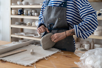 Pottery making process. Woman ceramist in apron creating crafted and artistic objects, cropped...