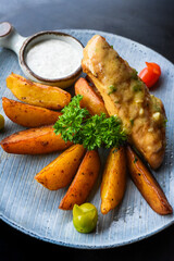 Chicken chop steak with french fries on blue plate isolated on black background side view