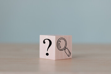 The wooden cube block with an illustration magnifying glass to analyze the question mark sign is...