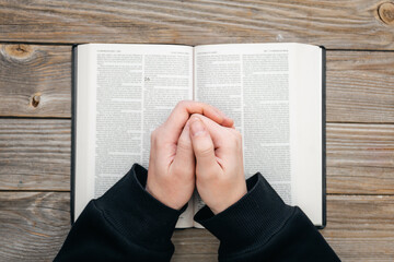 Close-up, christian read Bible. Hands folded in prayer on a Holy Bible, on wooden background, top...