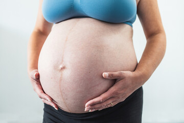 pregnant woman touching her bump in the latest stage of pregnancy, mid-section showing the belly...