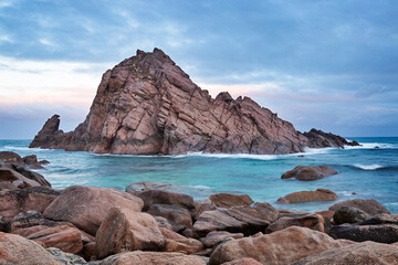 Fototapeta na wymiar Cloudy sunrise Sugar Loaf Rock. A large granite boulder in the Indian Ocean off the coast of south west of Western Australia