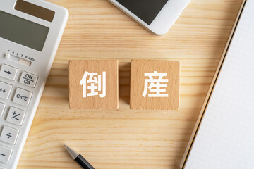 倒産と書かれたブロックが置かれたデスク
