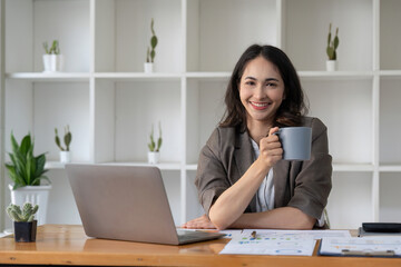 businesswoman sitting in office with digital tablet. Excited asian businesswoman raising hands to congratulate while working on laptop in office