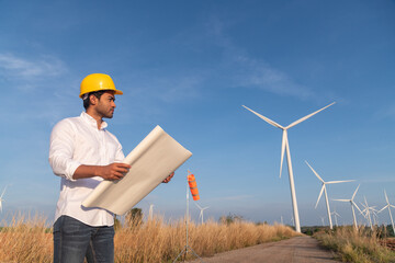 Engineer wearing uniform hold equipment box inspection work in wind turbine farms rotation to generate electricity energy. Green ecological power energy generation wind sustainable energy concept.