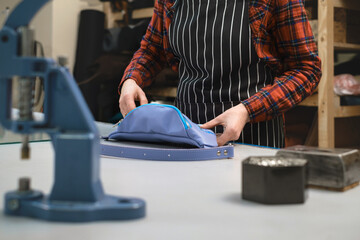 Sewing process. Tailor sewing bag at workshop. Woman creating accessories on workplace. Tailoring concept. Craft from eco leather. Close-up. Production. Small business making leather and canvas bags