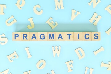 Study pragmatics in linguistics concept. Wooden blocks word typography flat lay in blue background.