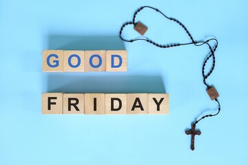 Good Friday holy week concept. Wooden blocks typography with rosary flat lay in blue background.