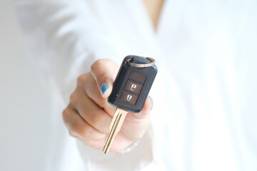 A woman is holding and showing the smart key of the car she handed over as a demonstration of car delivery.