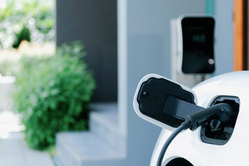 Closeup electric vehicle plugged-in with cable from charging point powered for progressive concept...