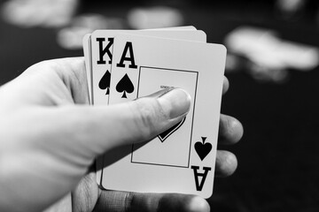 A closeup, black and white image of a man holding the Ace of Spades and King of Spades playing...