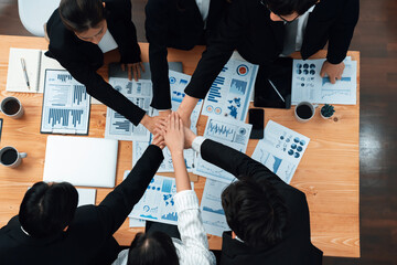 Top view cohesive group of business people join hands together, form circle over table filled with...